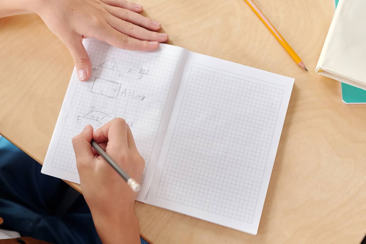 A class 8 notebook open on a desk beside a pencil, in window light.