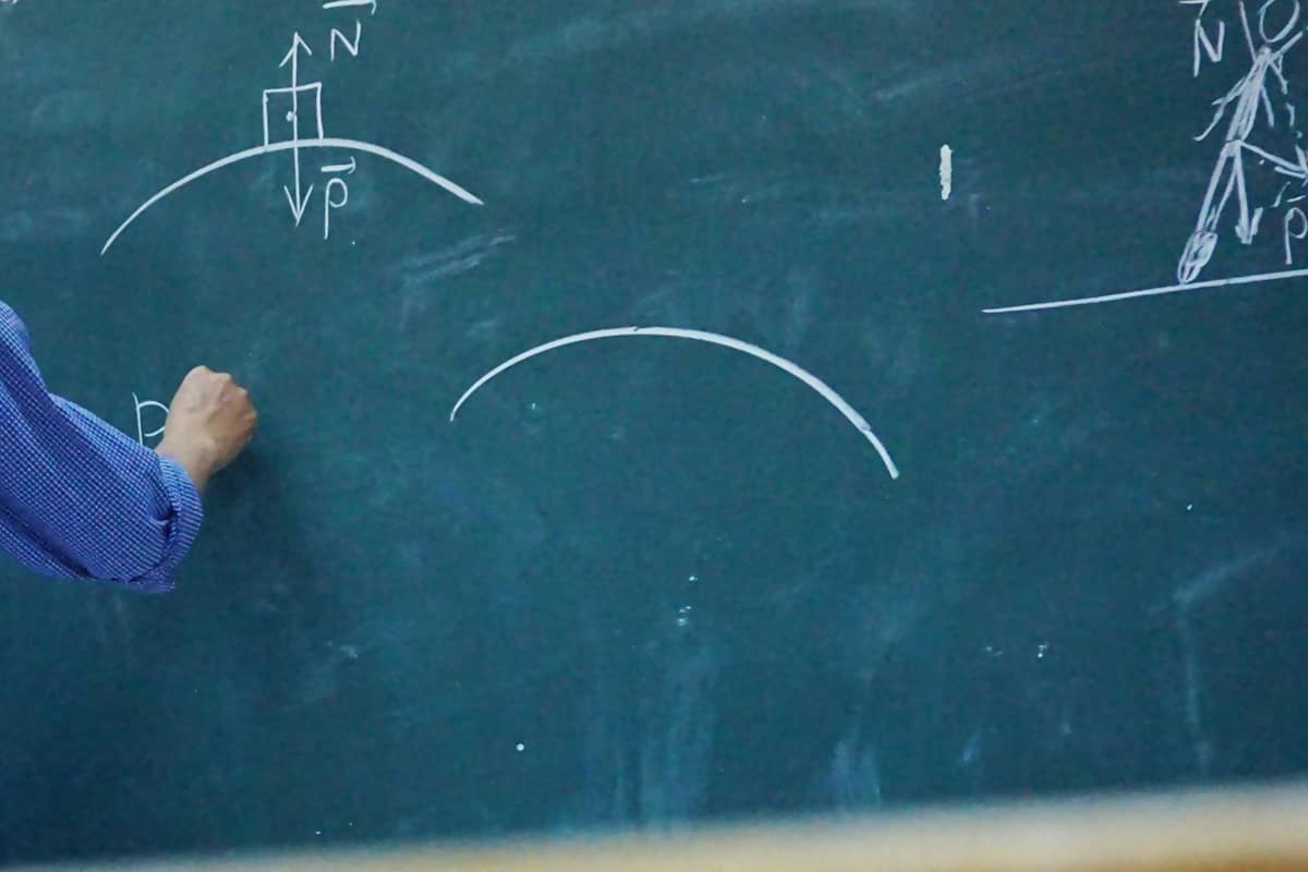 Chalk working of a mechanics problem on a blackboard, close up.