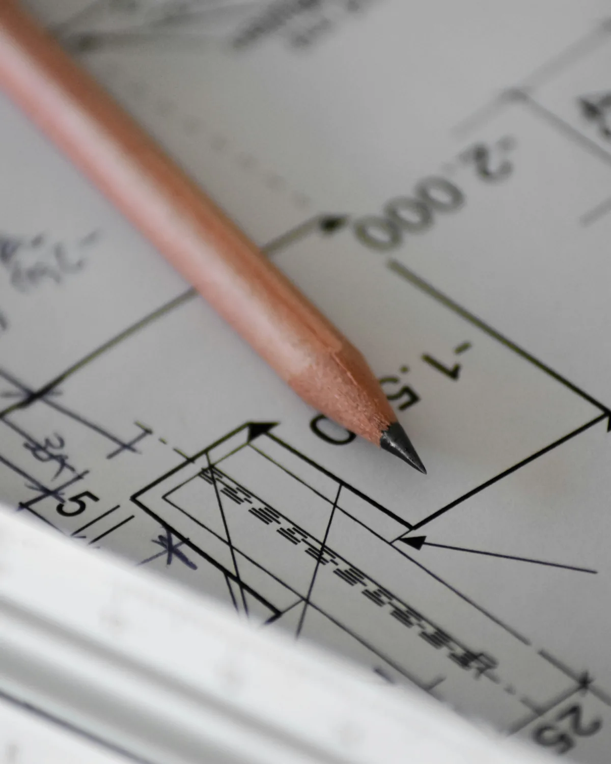 A pencil on a drawing with dimension marks, a scale ruler beside it.