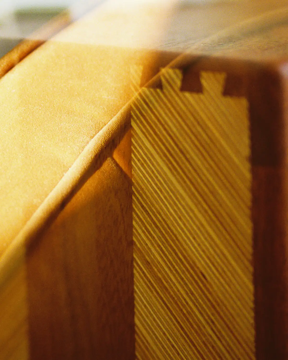 A close view of a dovetail corner on a teak frame, in warm light.