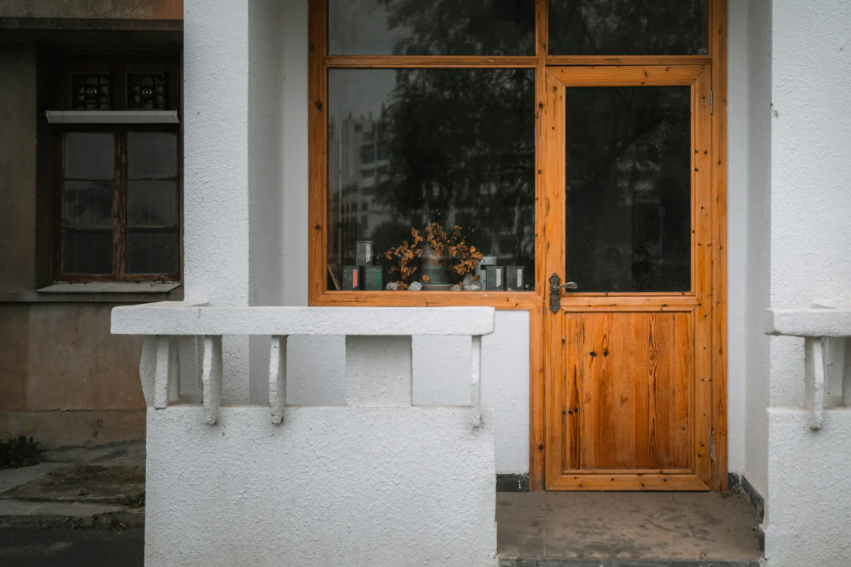 The showroom door from the road, a teak door and window in a white wall.