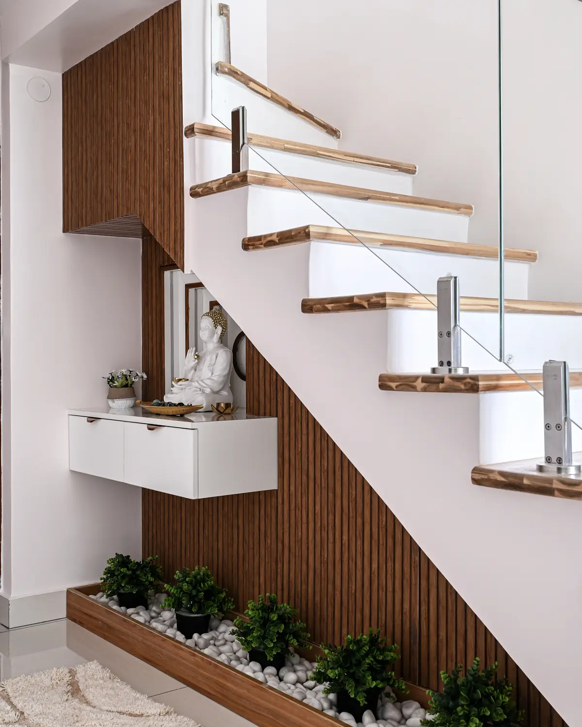 The staircase to the first floor, white treads edged in teak and a glass rail.