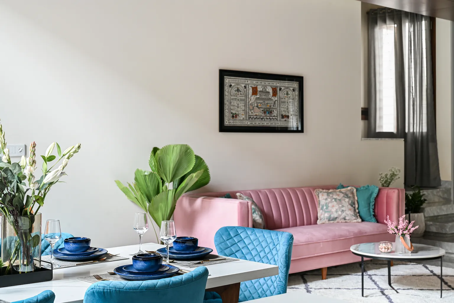 The ground floor: a dining table laid in front, a pink velvet sofa beyond.