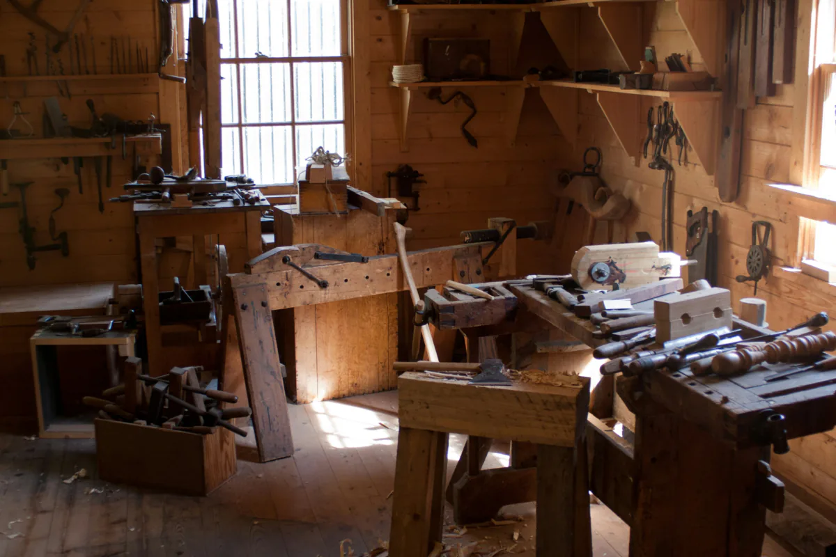The workshop: hand tools on the walls and worn benches in window light.