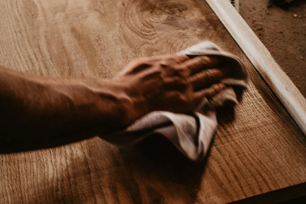A hand rubbing oil into a board with a cloth.