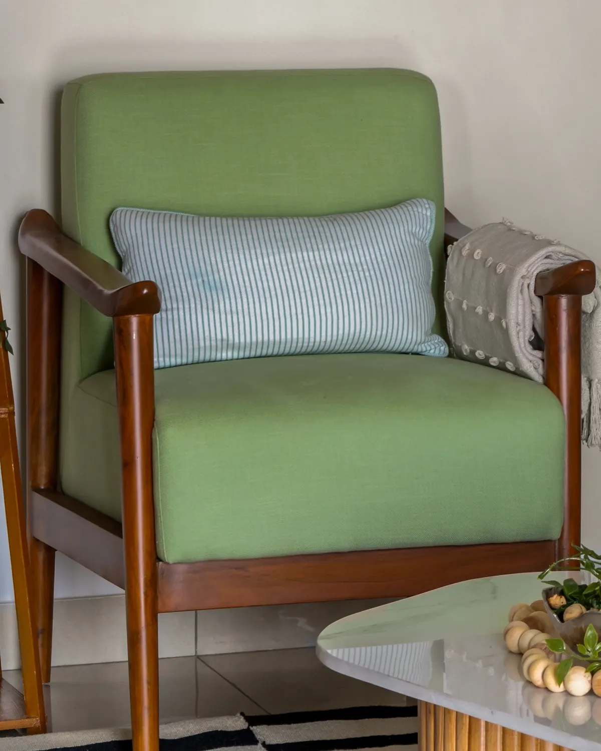 A teak armchair with sloping arms and a sage green cotton seat.