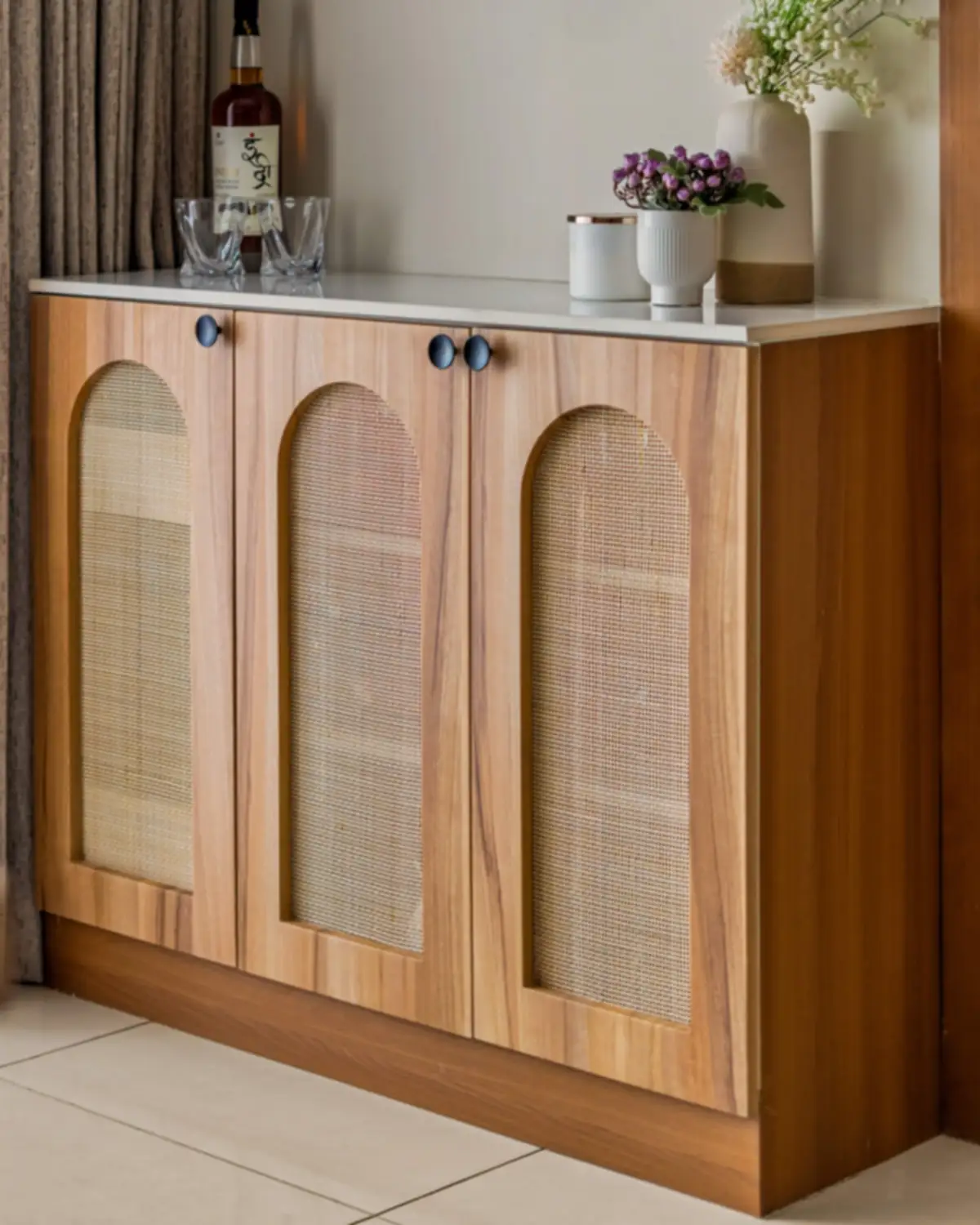 A teak cabinet with three arched cane doors and a white marble top.