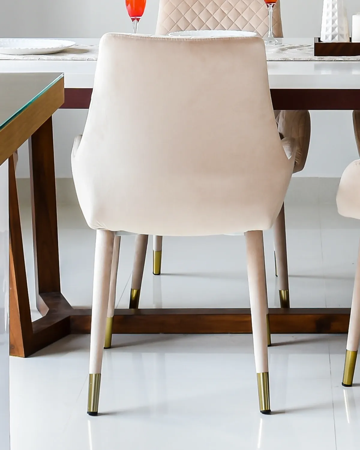 A cream velvet dining chair with a quilted back and brass-capped legs.