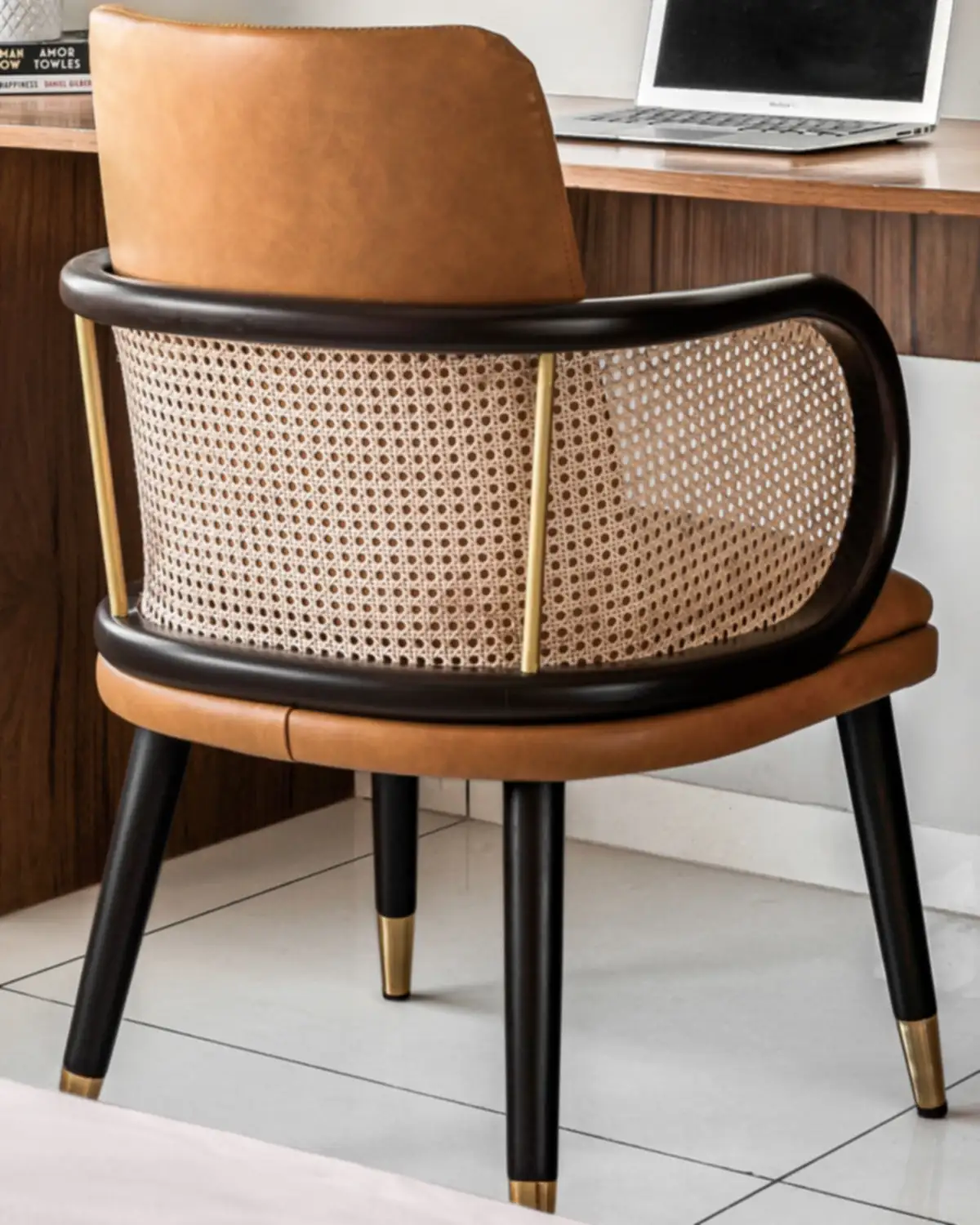 A study chair with a cane back in a curved black frame and a tan leather seat.