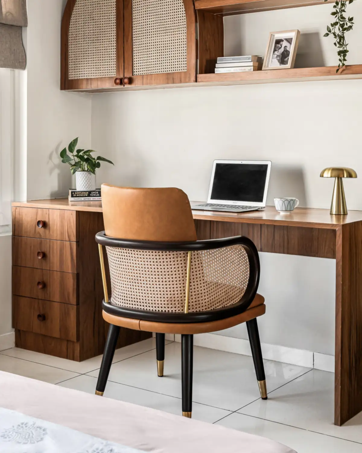 A teak study desk with a four-drawer pedestal and a waterfall leg, a laptop and a brass lamp on top.