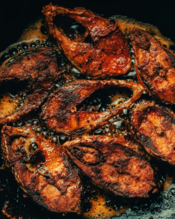 Slices of murrel fried dark in an iron pan.