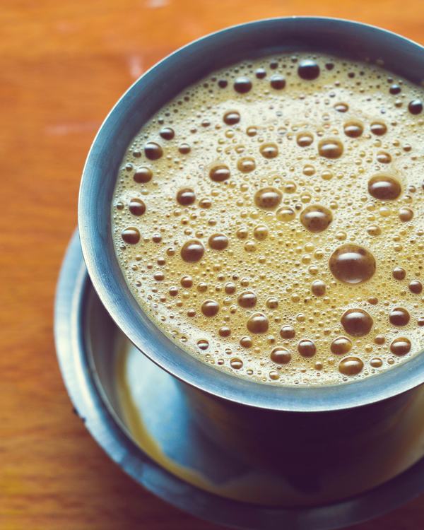 Filter coffee in a steel tumbler and dabara, froth at the rim.