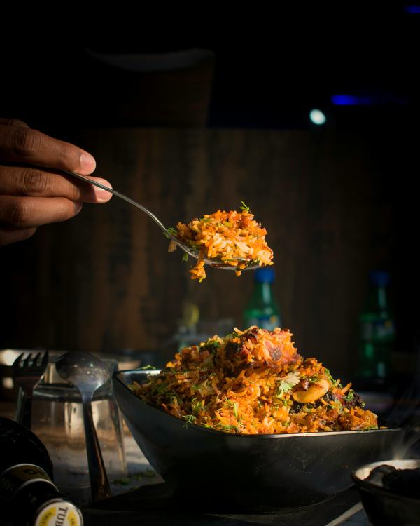 A spoonful of chicken biryani lifted from the pot.