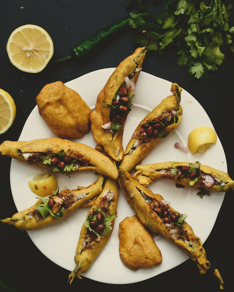 Mirchi bajji split open and fanned on a plate, lemon halves around it.