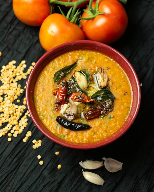 Tomato pappu in a clay bowl, a tempering of garlic and red chilli over it.