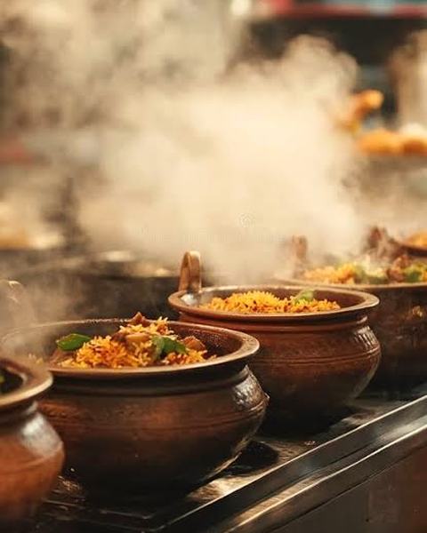 Clay pots of biryani steaming on the kitchen counter.