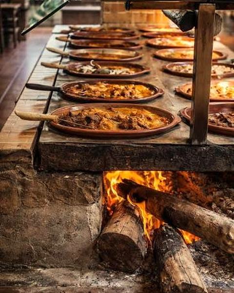 A wood fire burning under a row of clay dishes on a stone counter.