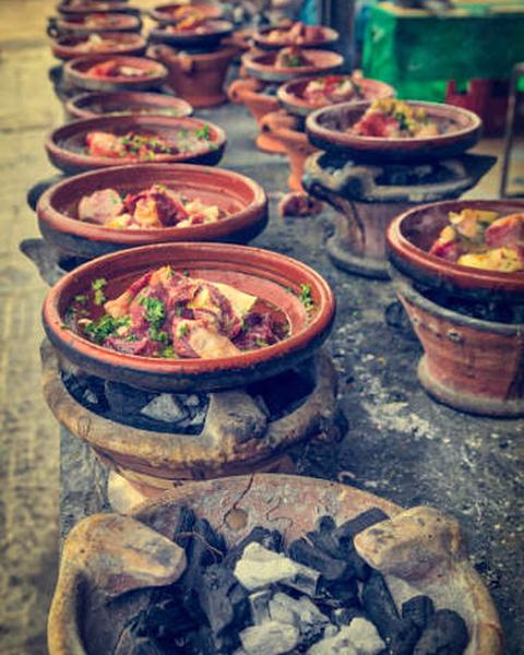 A row of clay pots of curry over small charcoal stoves.