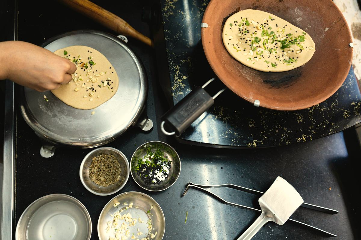 Rotis on a clay tawa at the counter, small steel bowls of filling beside them.