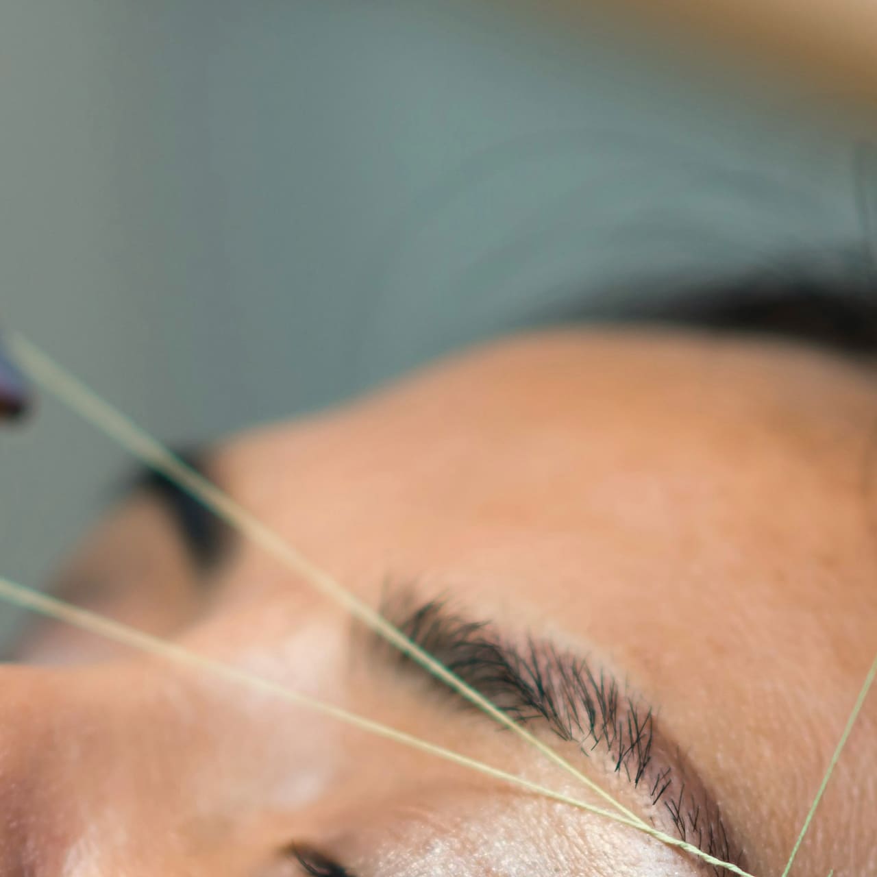 A thread held taut over an eyebrow during threading.