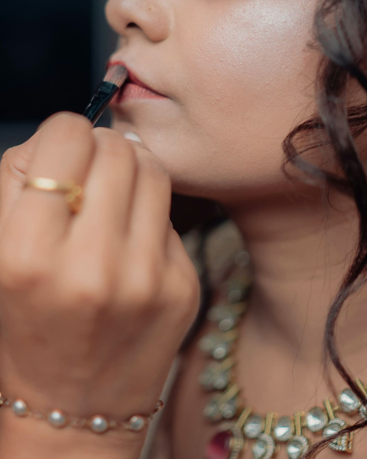 Sana at work, a lip brush in her hand, a bride in a kundan necklace.